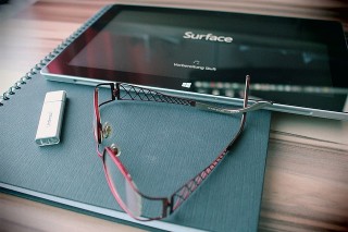 Microsoft Surface next to notebook and eyeglasses