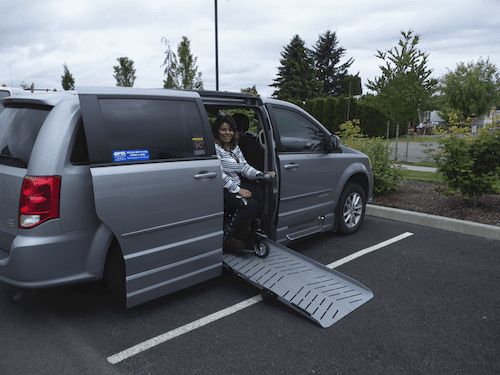Photo of a smiling client on a ramp of an adapted vehicle