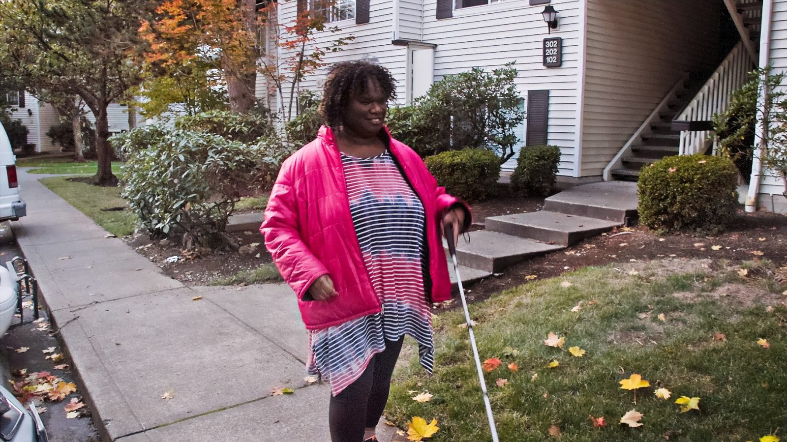 Photo of Alexandria walking on a sidewalk using a cane