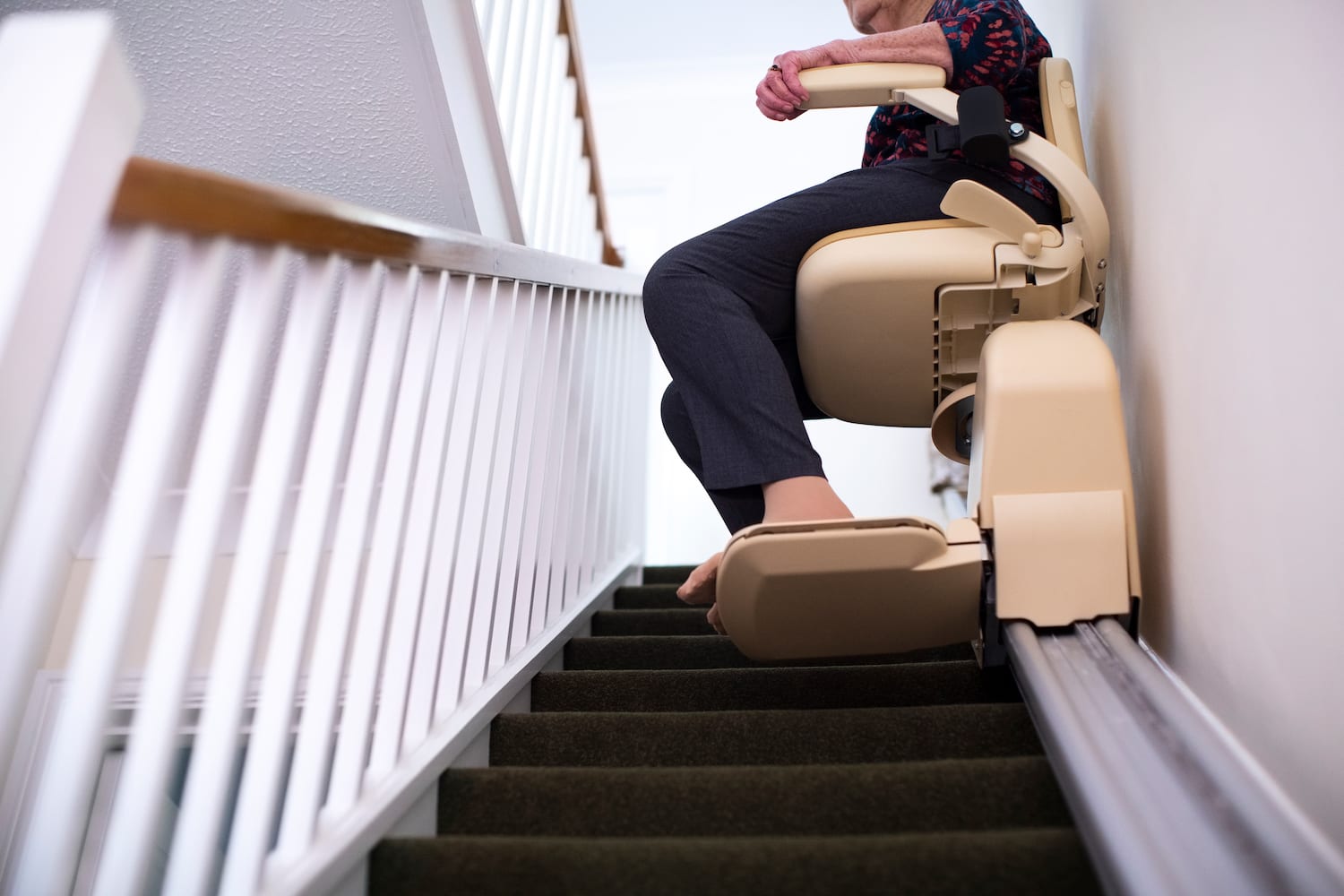 Image of woman sitting in stair lift going up the stairs