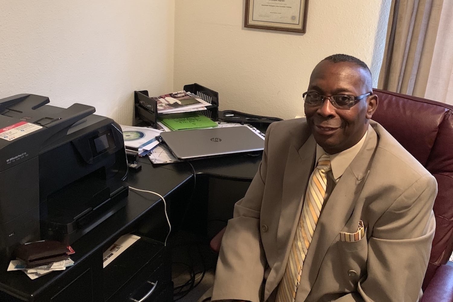 Photo of Artonyon in a suit sitting next to the computer equipment an NWAF Loan helped facilitate