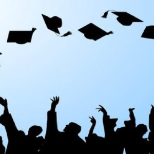 A silhouette of students throwing their hats in the air at graduation