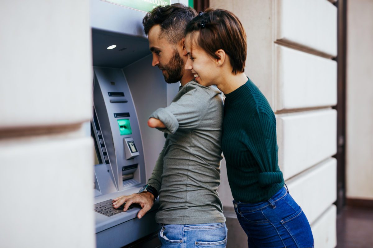 Disabled couple using ATM machine in city street