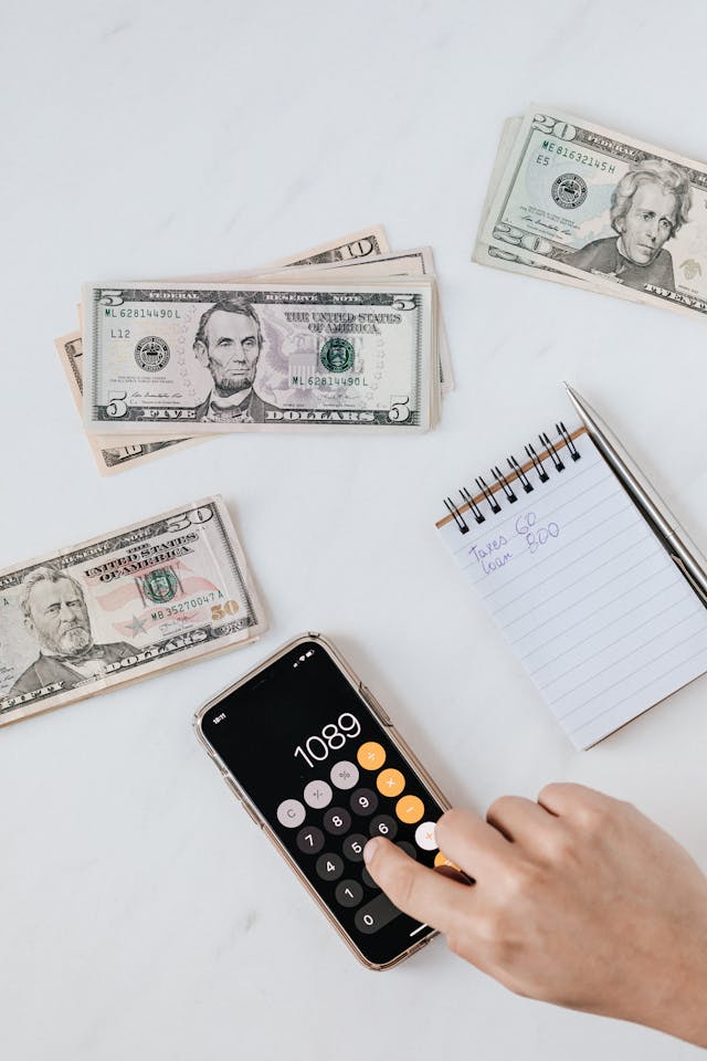 Calculator on phone open surrounded by dollar bills