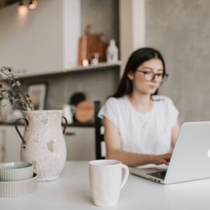 Woman with glasses working on computer in kitchen