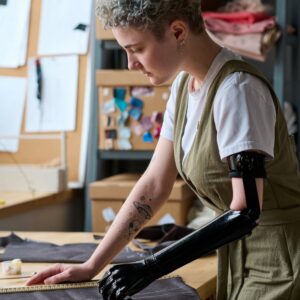 Young businesswoman with a prosthetic arm cutting textiles